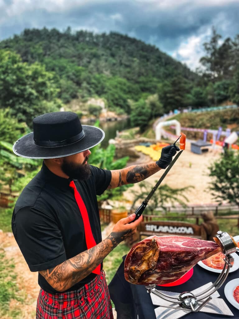 Cortador profesional de jamón de Galician Ham Carver en acción en la Ribeira Sacra, Lugo, ofreciendo servicio de corte de jamón ibérico al aire libre con vistas al río Miño
