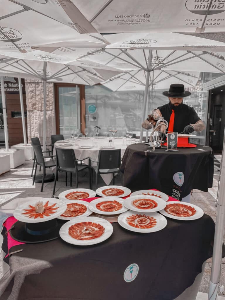 Julio García realizando corte artístico de jamón en evento elegante bajo carpa en Galicia, ideal para bodas, aniversarios y celebraciones en A Coruña, Lugo, Ourense y Pontevedra.