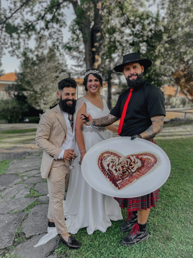 Julio García de Galician Ham Carver junto a una pareja de novios en una boda, presentando una obra de arte en jamón en forma de corazón