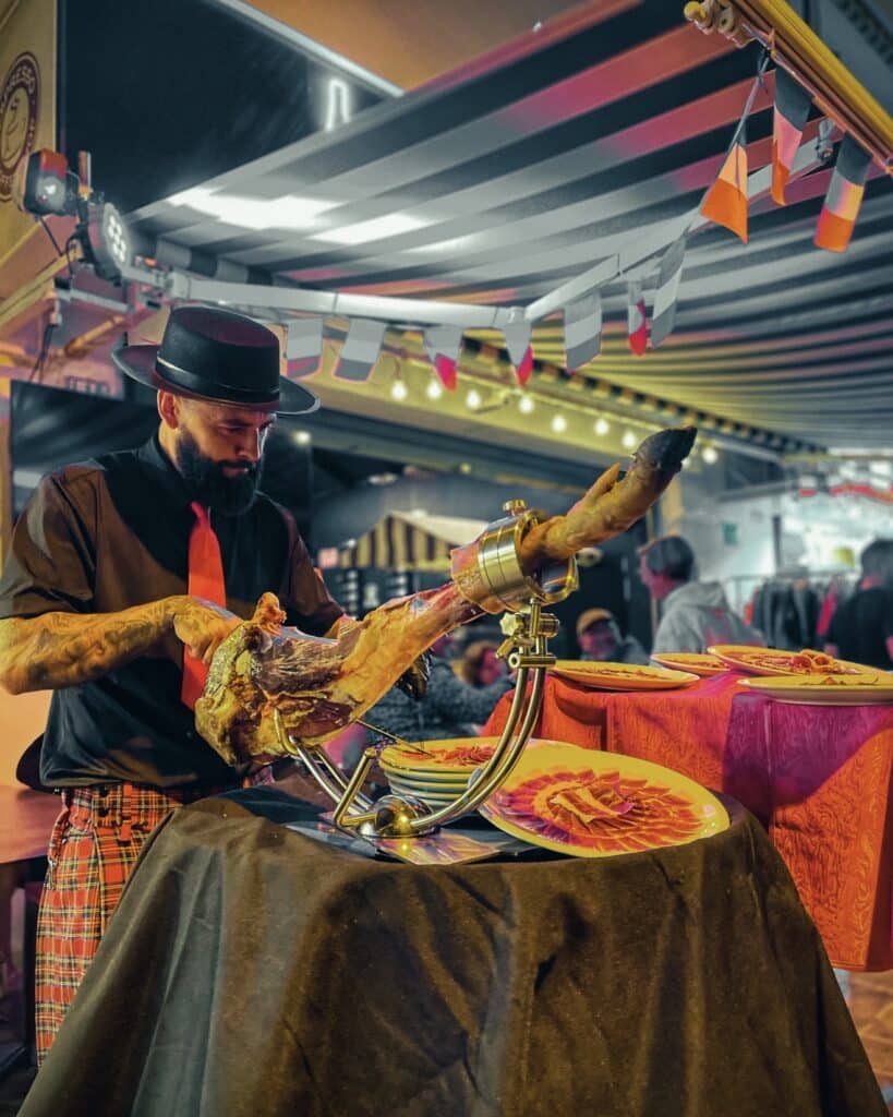 Julio García de Galician Ham Carver cortando jamón ibérico en evento nocturno.
