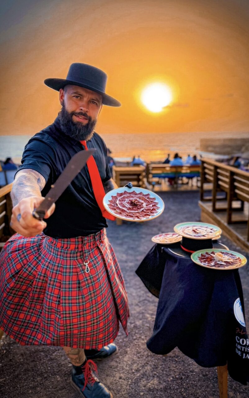 Julio García de Galician Ham Carver sirviendo jamón ibérico artesanal al atardecer en Fuerteventura, para bodas, comuniones y eventos en Gran Canaria, Tenerife, Lanzarote, Fuerteventura, La Palma, El Hierro, La Gomera, La Graciosa y todo el archipiélago canario.