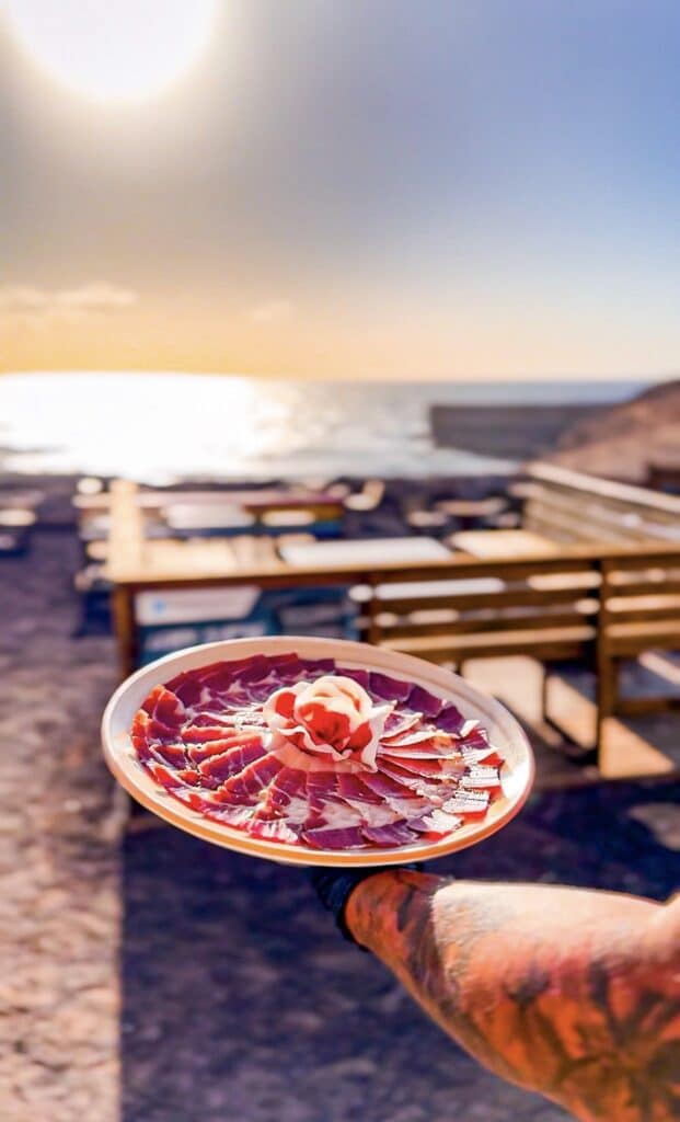 Plato de jamón ibérico tallado en forma de rosa por Julio García de Galician Ham Carver en un evento frente al mar en Fuerteventura, disponible para bodas, comuniones y celebraciones en Corralejo, Caleta de Fuste, Morro Jable y Puerto del Rosario.