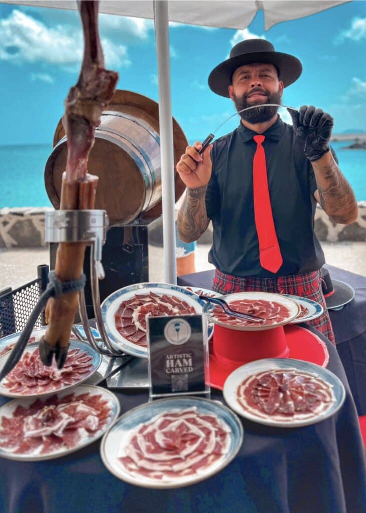 Julio García, cortador de jamón profesional de Galician Ham Carver en Gran Canaria, preparando platos de jamón ibérico artístico para eventos, bodas y celebraciones junto al mar.