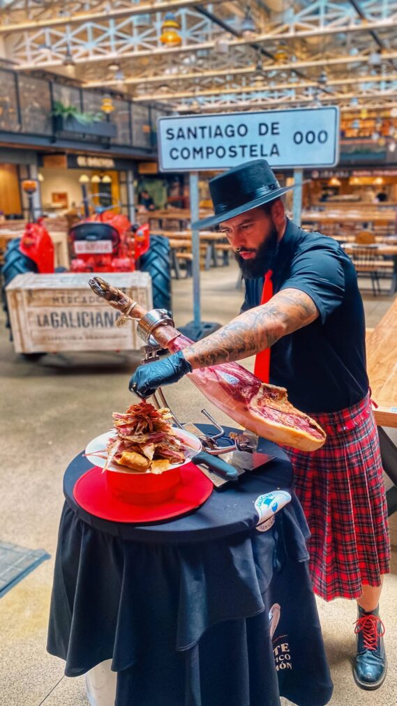 Cortador artístico de jamón en Santiago de Compostela durante evento en el Mercado La Galiciana, ofreciendo experiencia gourmet profesional para bodas, eventos y celebraciones en A Coruña y Galicia.