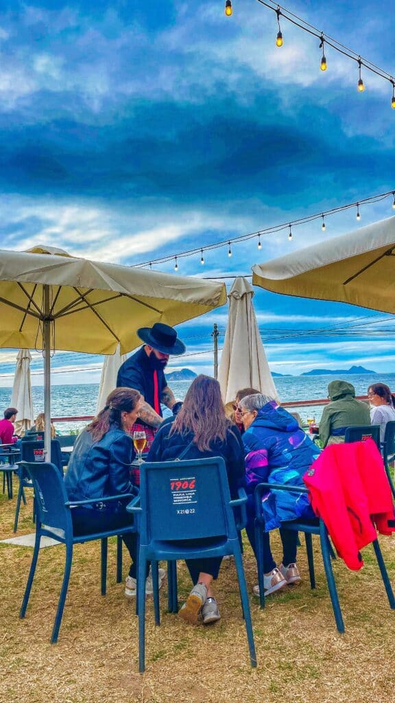 Cortador profesional de jamón en evento gastronómico frente al mar en Patos, Nigrán, con vistas a las Islas Cíes.