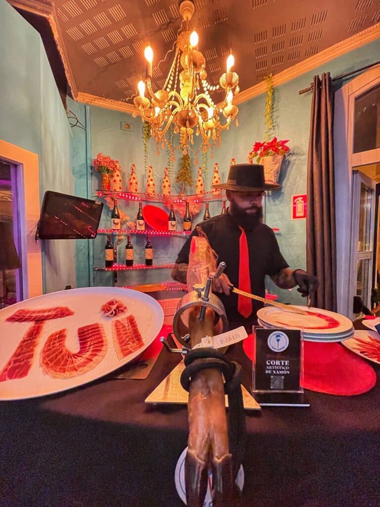 Galician Ham Carver realizando corte artístico de jamón ibérico en un evento exclusivo en Tui, Pontevedra, combinando gastronomía gallega y presentación personalizada con el nombre de la ciudad en jamón.