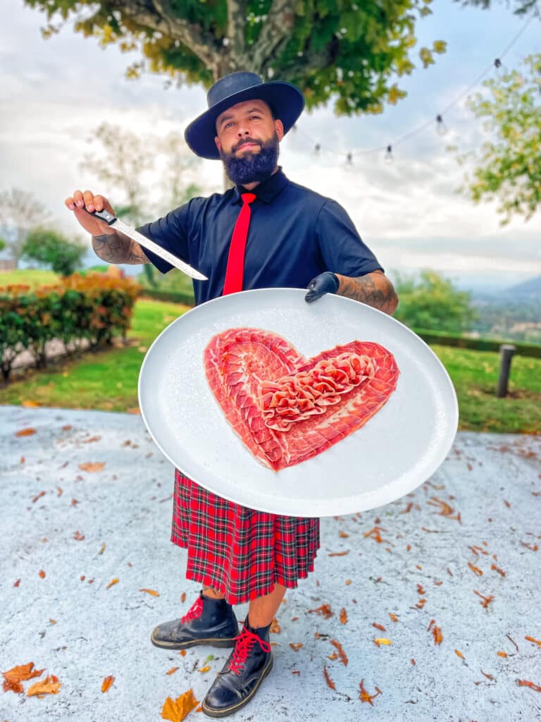 Julio García, maestro jamonero de Galician Ham Carver, sosteniendo un plato con corte artístico de jamón en forma de corazón para bodas y eventos en Galicia.
